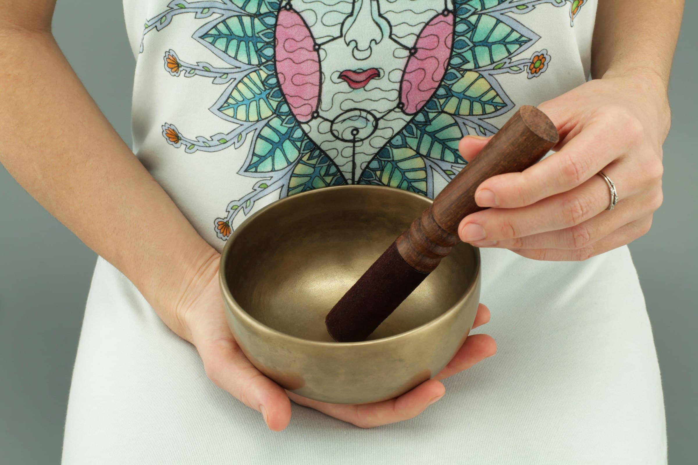 Hands holding a singing bowl and wooden mallet